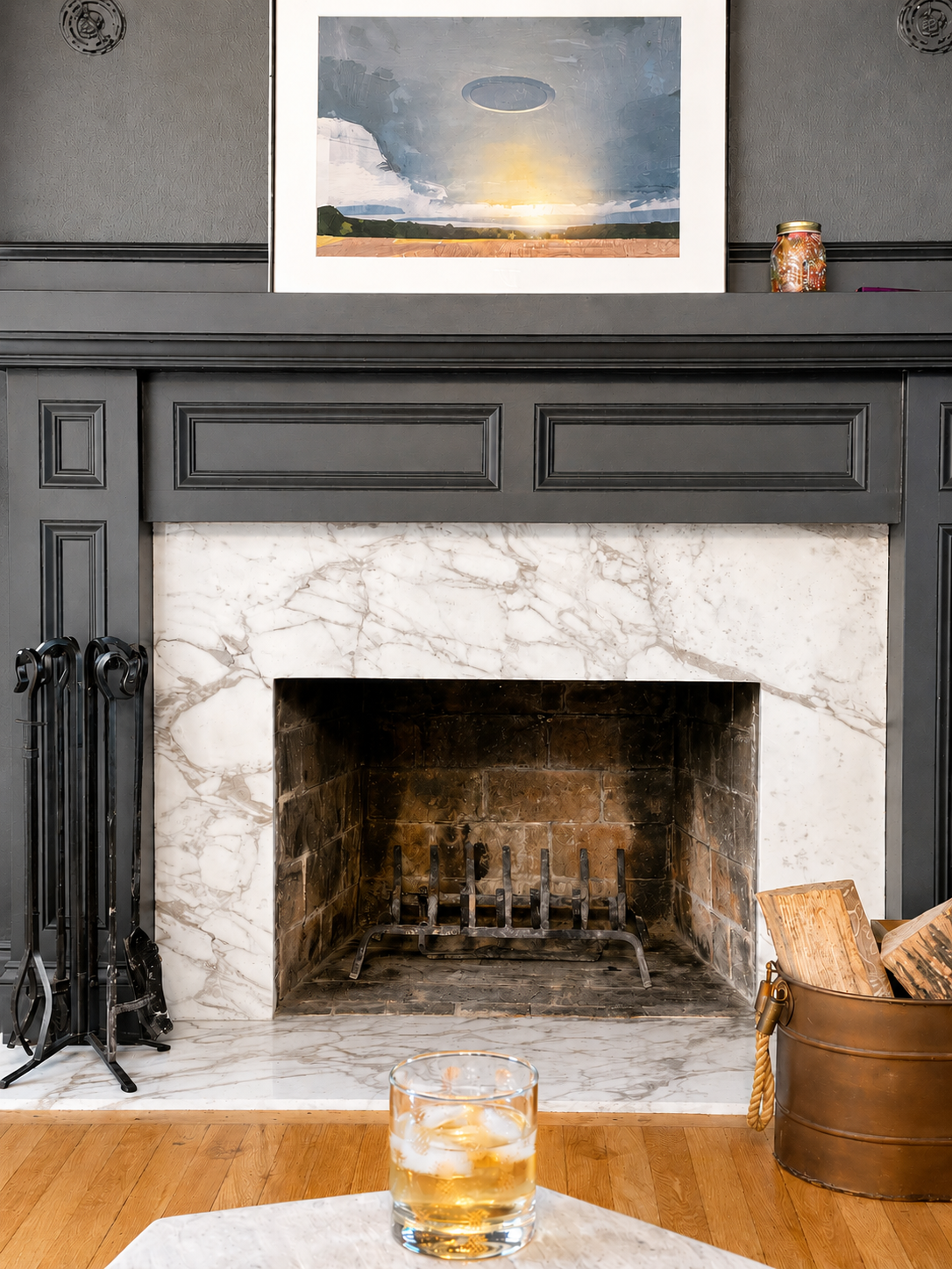 Traditional marble fireplace with dark wood mantel and fireplace tools.