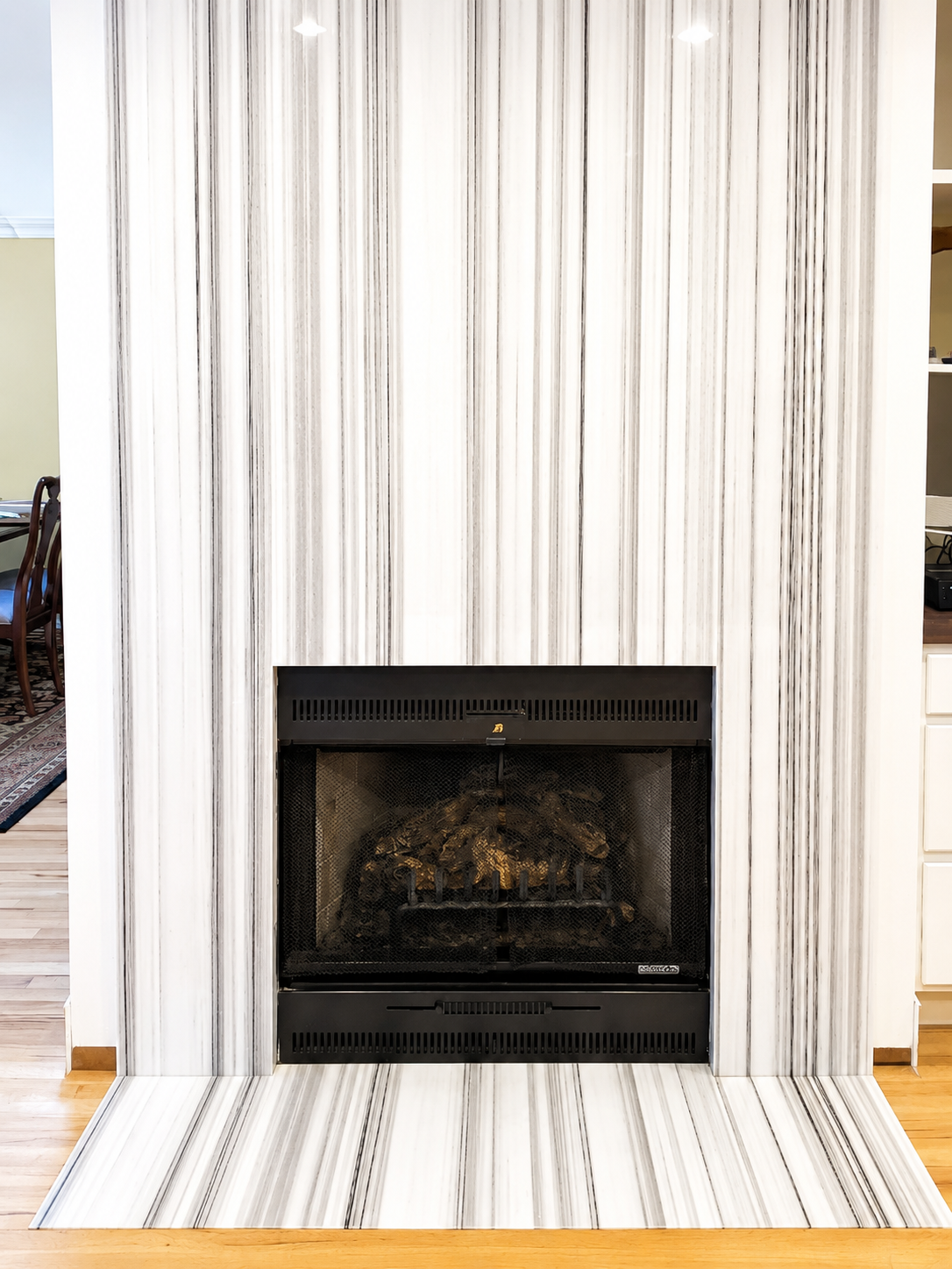 Modern fireplace with white and gray marble surround and hearth.