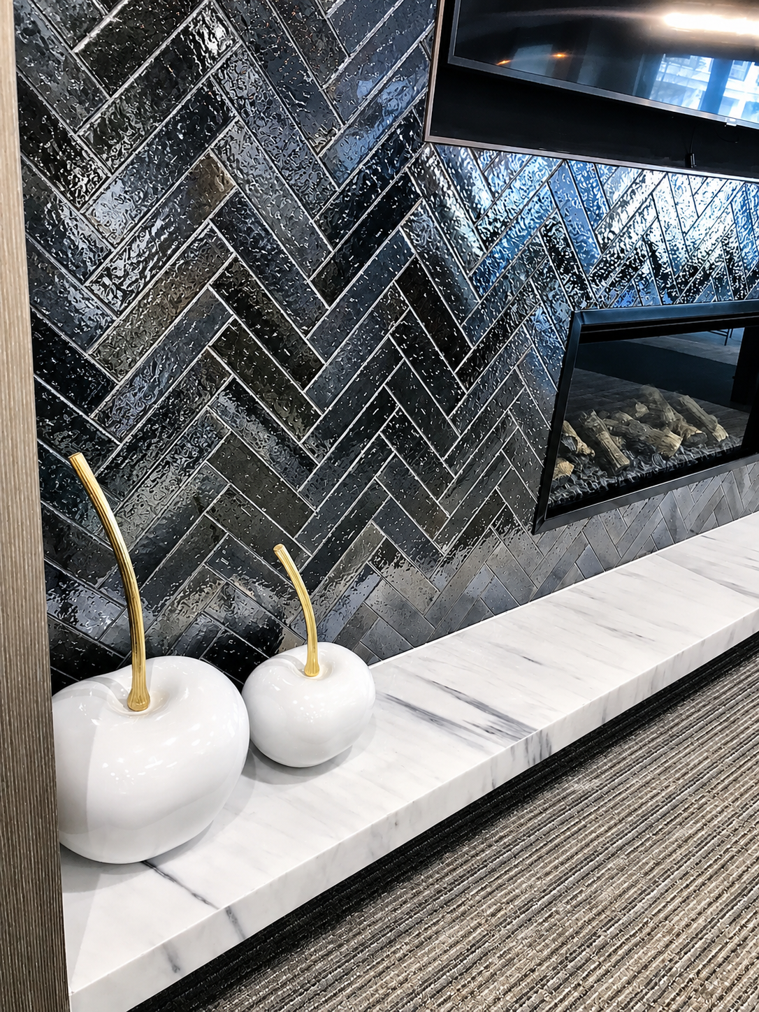 Black herringbone tile fireplace with marble hearth and modern decor.