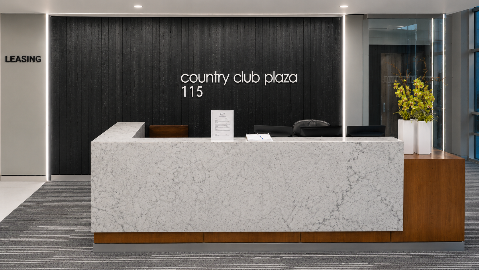 Modern reception desk with marble front and black feature wall.